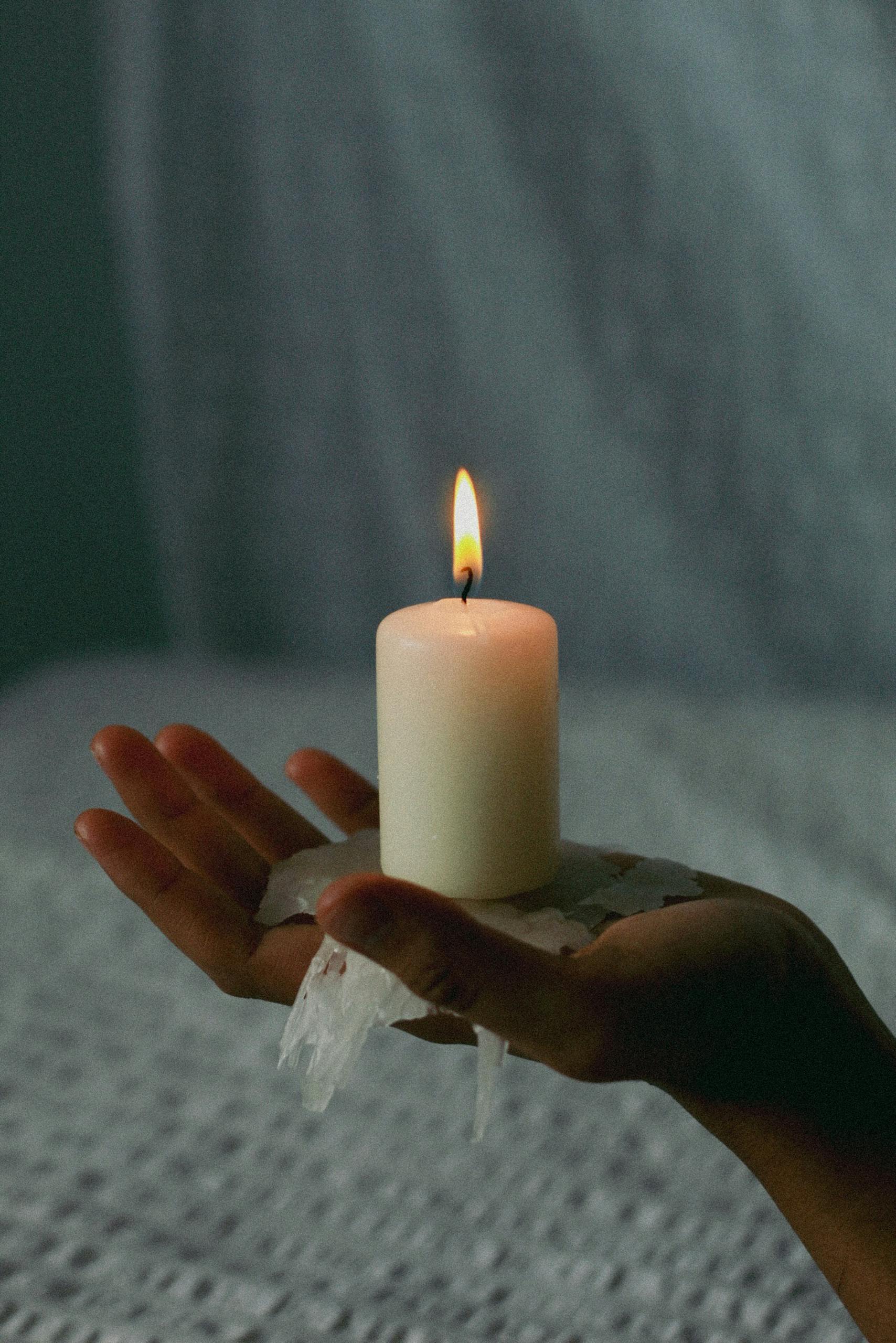 A soothing image of hands holding a lit wax candle, symbolizing serenity and warmth.